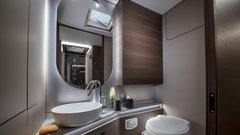 Velika kopalnica z ločenim umivalnikom in tuš kabino s tuš stolpom Alde, stenskim ogrevanjem, držalom za brisače in obešalniki.