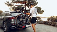 Male cyclist loading his bicycle on a rack of his crossover car