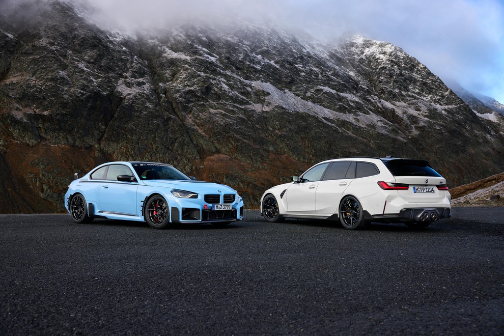 Modri BMW M2 in beli M3 Touring, parkirana v gorah.